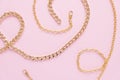 A gold chain laid out in the shape of a heart on a pink background Royalty Free Stock Photo
