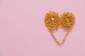 A gold chain laid out in the shape of a heart on a pink background Royalty Free Stock Photo