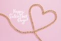 A gold chain laid out in the shape of a heart on a pink background Royalty Free Stock Photo