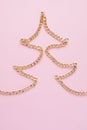 A gold chain laid out in the shape of a x-mas tree on a pink background Royalty Free Stock Photo