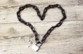 Chain heart shape on the lock on wooden background.