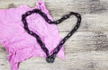 Chain heart shape on pink rag on wooden background.