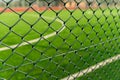 Through the chain-link fence, a blurred soccer field emerges, where passion for the game and dreams of victory come to