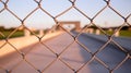 Chain link fence in the foreground with an arched structure and pathway in the soft focus background Royalty Free Stock Photo