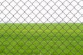Chain link fence with green grass field on background. Close-up view from behind the fence. Royalty Free Stock Photo