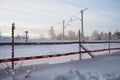 A chain-link fence near the railway. Winter short polar frosty day. Snow drifts and drifts on the railway tracks. Polar