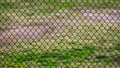 Chain link fence in a sports park with grassy field behind it