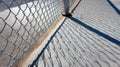 Chain-link fence on sunlit concrete with intricate shadow patterns captured in the afternoon light Royalty Free Stock Photo