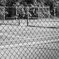 Chain-link Fence with Tennis Court in Background Royalty Free Stock Photo