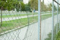 Chain link wire fence with hole in the line with street. Royalty Free Stock Photo