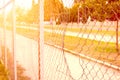 Chain link wire fence with hole parallel with the street and with sunlight. Royalty Free Stock Photo