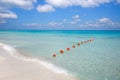Chain of orange buoys against the blue sea and white beach sand