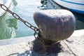 Chain tied on a bollard. Mooring rope wrapped around the cleat on sea background. Metal capstan in harbor for the mooring of yacht Royalty Free Stock Photo