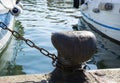 Chain tied on a bollard. Mooring rope wrapped around the cleat on sea background. Metal capstan in harbor for the mooring of yacht Royalty Free Stock Photo