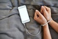 Chained to technology. High angle shot of an unrecognizable persons hands bound by a cellphone cable. Royalty Free Stock Photo