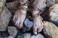 Chains with a lock on the legs of a slave amidst stones. Chains at the ankle. The symbol of slavery Royalty Free Stock Photo