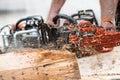 Chainsaw in action with flying sawdust and motion blur, man is c