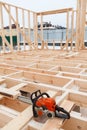 Chainsaw lying on grillage beams of timber house. Construction site at winter season, nobody Royalty Free Stock Photo