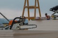 Chainsaw resting on a house construction site, with other tools and gadgets visible around on a dull day