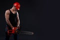 Chainsaw and young worker. The naked man broke the chainsaw. Attractive guy with tool on black background. Builder or lumberjack, Royalty Free Stock Photo