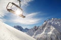 Chair lift on a mountainside on background of blue sky, snow-capped mountains and a bright winter sun Royalty Free Stock Photo