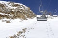 Chair lift move up and cableway in the foreground against the background of snow-capped mountains and blue sky.Austrian Alps in Royalty Free Stock Photo