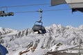 Chair lift in ski resort with snowcapped mountain peaks in the background Royalty Free Stock Photo