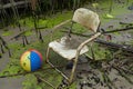 chair with a lost beach ball in a tangle of algae and refuse