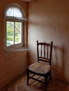 A chair next to a corner window with webs