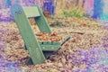 Chair in park under leaves with lens flare effect. Vintage tone