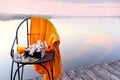 A chair with sea buckthorn tea and a book on the shore of a calm lake at sunset. The atmosphere of rest, relaxation, countryside w Royalty Free Stock Photo