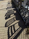 Chair Shadows with Fence on Concrete Sidewalk