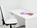 Chair and white table with purple stethoscope and red medical journal in doctor`s office. Note