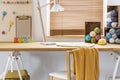 Chair with yellow blanket at desk with lamp and colorful yarns in workspace interior. Real photo