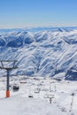 Chairlift on the background of snow ridges and blue sky. The concept of active winter recreation Royalty Free Stock Photo