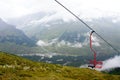 Chairlift over the green valley. Caucasian mountains with clouds and fog in the background Royalty Free Stock Photo