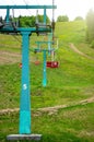 Chairlift at the ski resort, view from below. Elevator in the summer season. Moving rope and chairs. Green pine forest in the Royalty Free Stock Photo