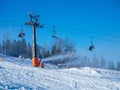 Chairlift, skiers and snow cannons in action