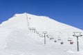 The chairlift to the top of the mountain. To the left of it and under it is a ski slope. In the background is a clear Royalty Free Stock Photo