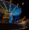 Chairoplane on a festival with blue lights and the moon in background