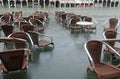 chairs of an alfresco cafe submerged by water during high tide i Royalty Free Stock Photo