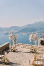 Chairs stand in front of a wedding semi-arch on an observation deck over the sea