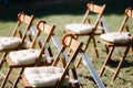 Chairs stand on the green grass in the area of the wedding ceremony, white umbrellas hang on the chairs Royalty Free Stock Photo