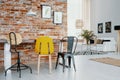 Chairs at table against red brick wall with posters in modern apartment interior with lamp. Real photo Royalty Free Stock Photo