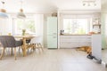 Chairs at table under lamps in bright kitchen interior with frid