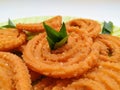 Chakli in a Green Plate on White Background. Indian Snack Chakli or chakali made from deep frying portions of a lentil