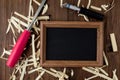 A chalk board with a black surface lies next to a wood carving set and a chisel