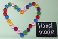 Chalk Board with the inscription `handmade` surrounded by a heart of colored buttons on a light background Royalty Free Stock Photo