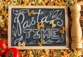 Chalk board sign Pasta Time on a wooden tabletop with raw farfalle, fresh tomatoes and black pepper Royalty Free Stock Photo