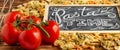 Chalk board sign Pasta Time on a wooden tabletop with raw farfalle, fresh tomatoes and black pepper Royalty Free Stock Photo